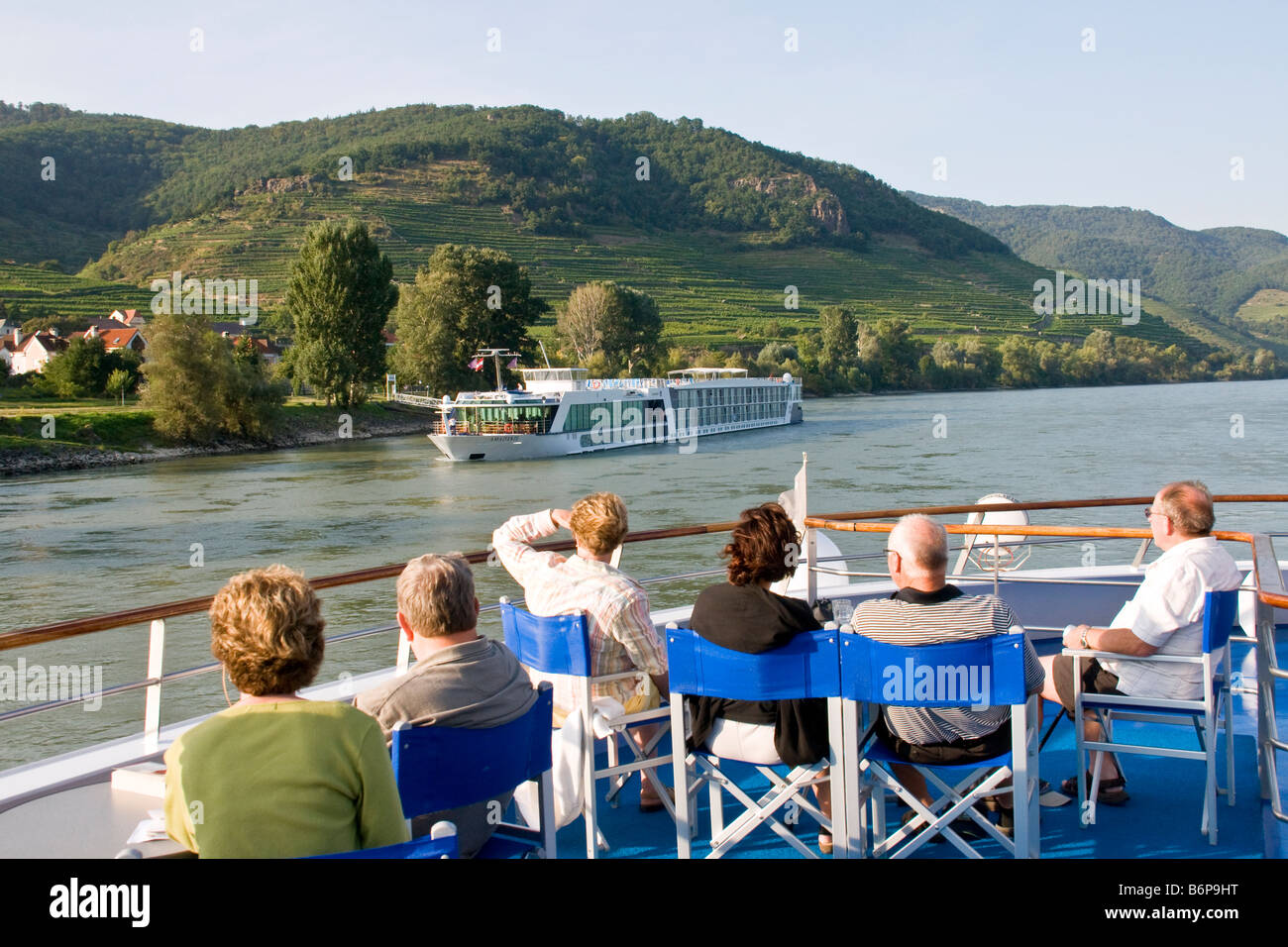 Danube River cruise ship passengers viewing MS Amadante cruising past scenic Wachau Valley village Stock Photo