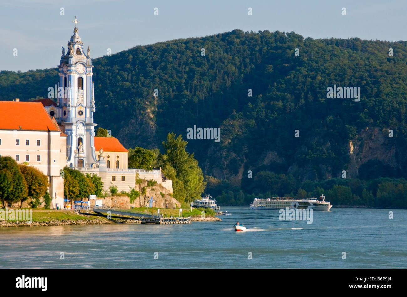 Durnstein village on Danube River with river cruise ship passing church formerly an Augustinian monastery Stock Photo