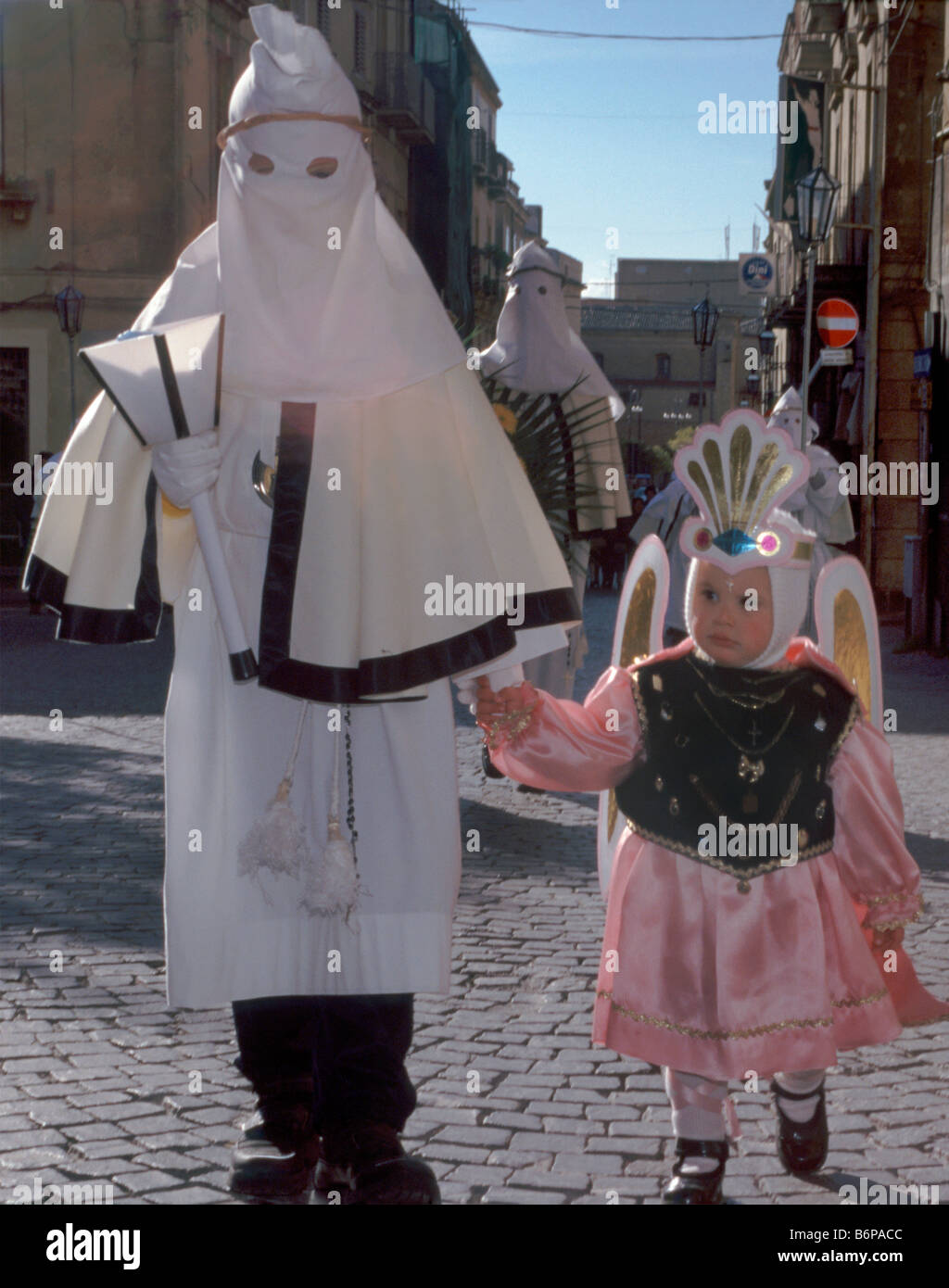Small child dressed as angel and penitents at Settimana Santa Holy Week Procession on Palm Sunday in Enna Sicily Italy Stock Photo