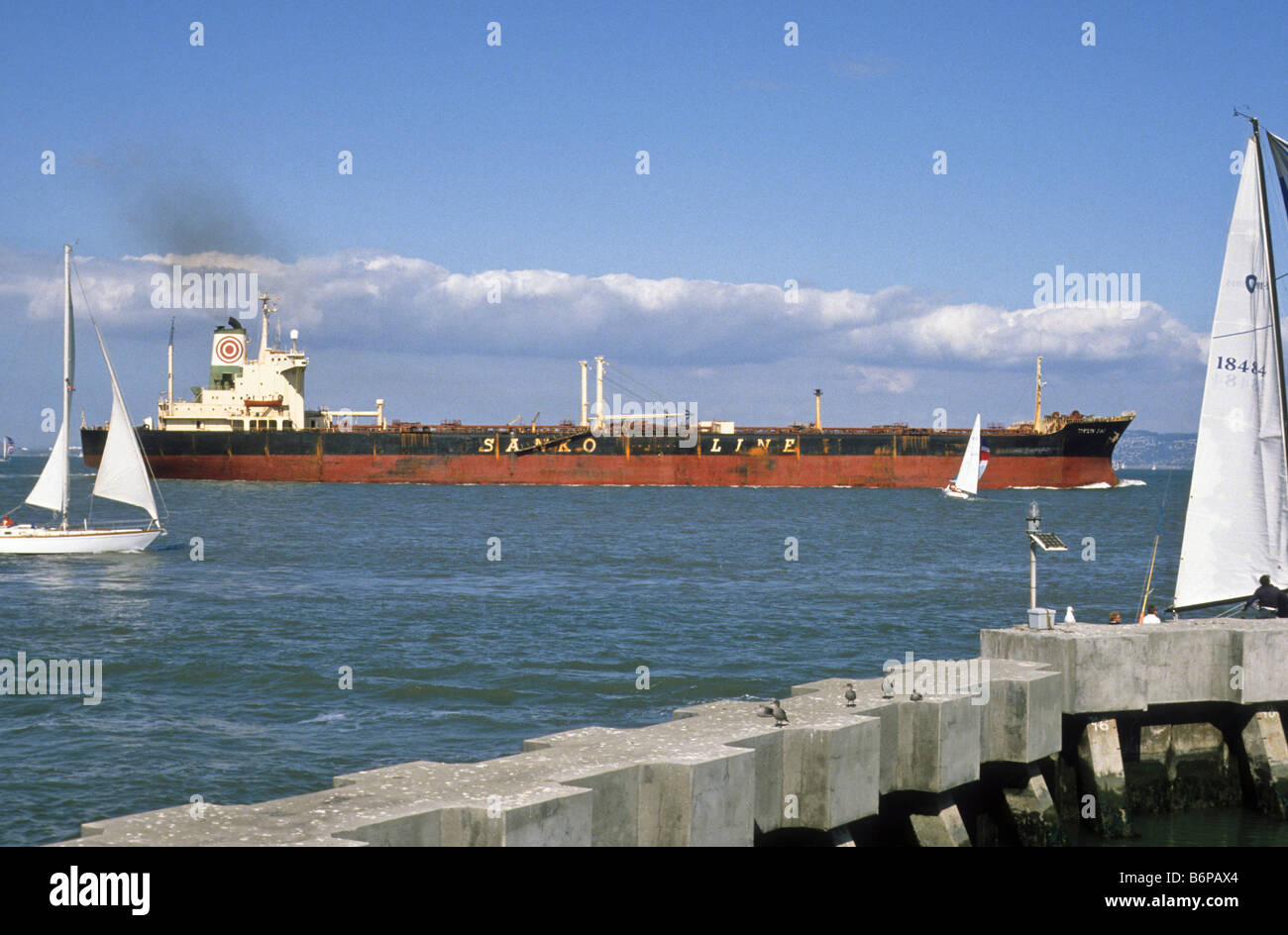 Oil tanker ship glides past recreational sailboats in San Francisco Harbor. Stock Photo