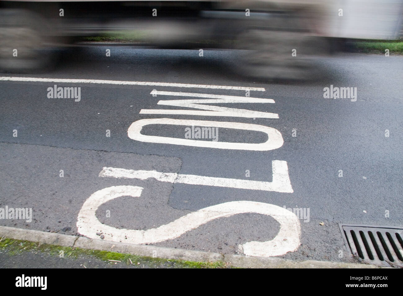 Car in motion blur photographed driving by a SLOW sign in the road Stock Photo