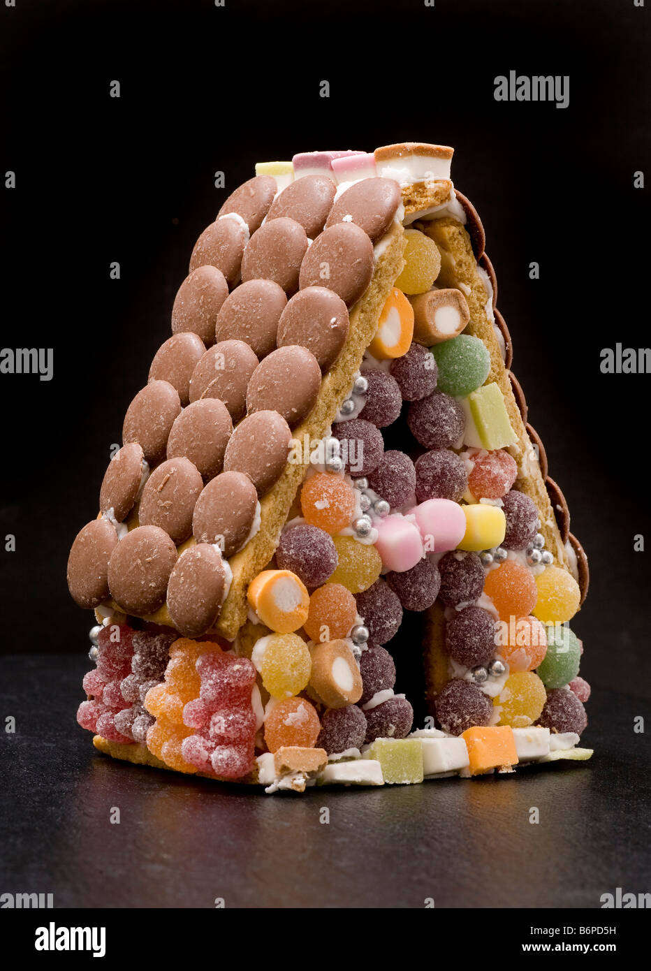 Gingerbread confectionary house with candy sweets tiled walls, chocolate button roof tiles. Stock Photo