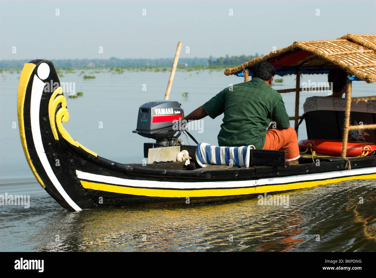 Outboard engine powered traditional boat ferrying passengers on backwaters of Vembanad Lake Kerala India Stock Photo