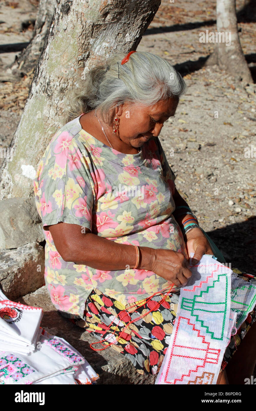 Senior Mayan woman doing needlework of Chichen Itza on the heritage pyramid site in Mexico Stock Photo