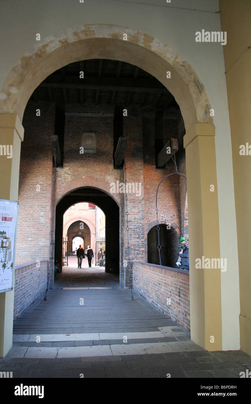 Couple entering Castello Estense through arched gateways, Ferrara, Italy Stock Photo