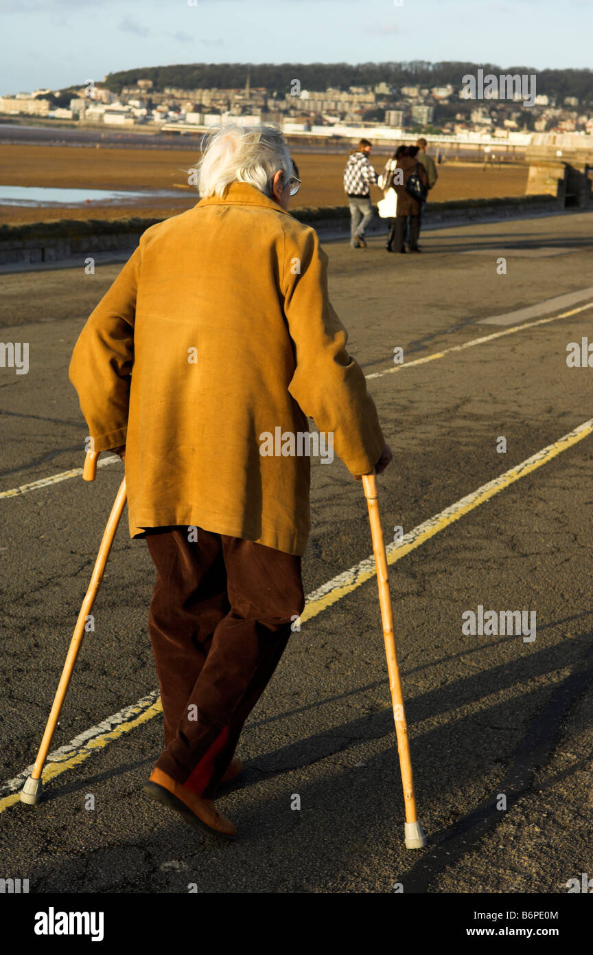 Senior woman walking with two sticks at Royal Parade Weston Super Mare North Somerset England Stock Photo