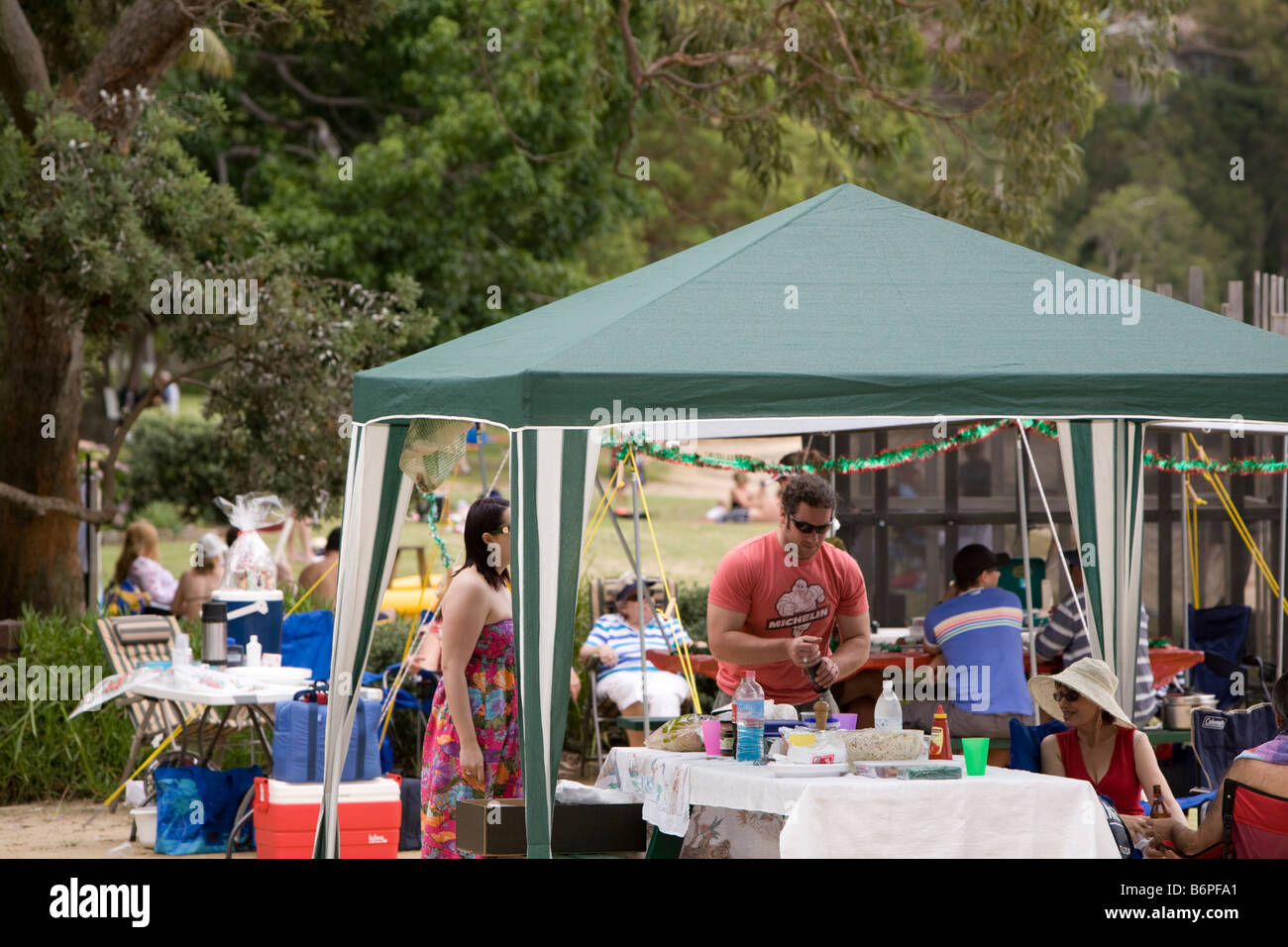 families having christmas barbecue lunch under a canopy on one of