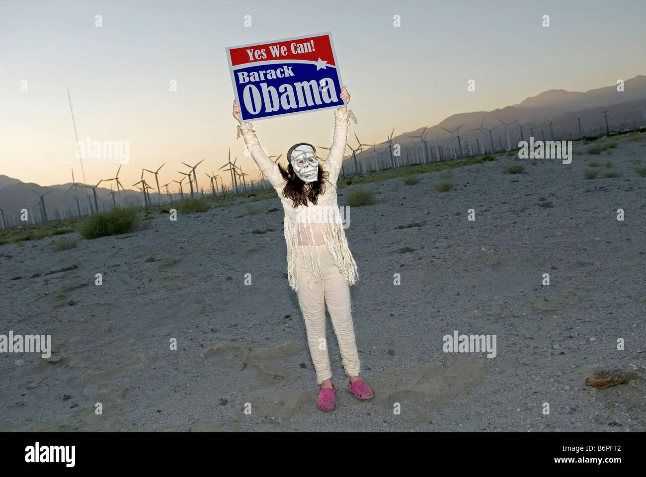 Young girl in Halloween costume holding up Barak Obama 'Yes We Can' election banner near Palm Springs California, USA. Stock Photo