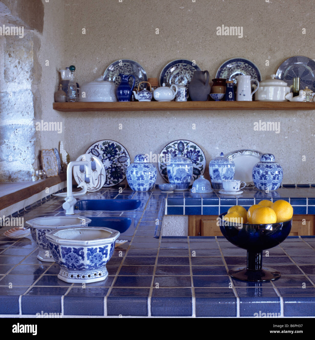 Blue tiled worktop and collection of blue and white china on shelves and worktop in cottage kitchen Stock Photo