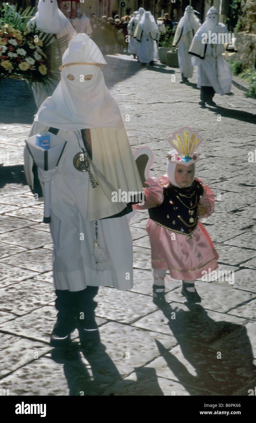 Small child dressed as angel and penitents at Settimana Santa Holy Week Procession on Palm Sunday in Enna Sicily Italy Stock Photo