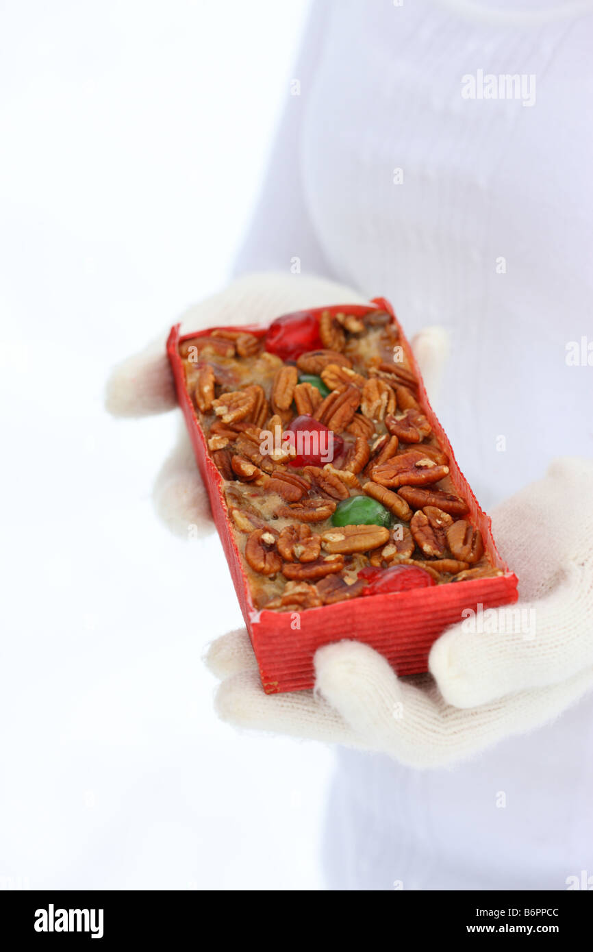 Hands with winter gloves holding Christmas Fruitcake Stock Photo