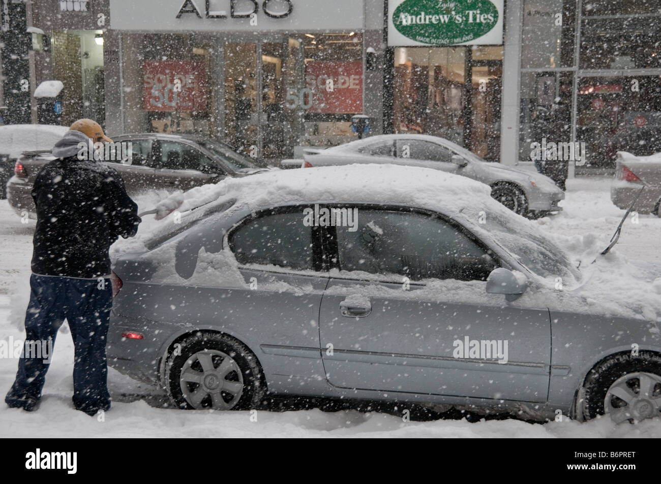 Man removing snow from car during a snowstorm Montreal Canada Stock Photo