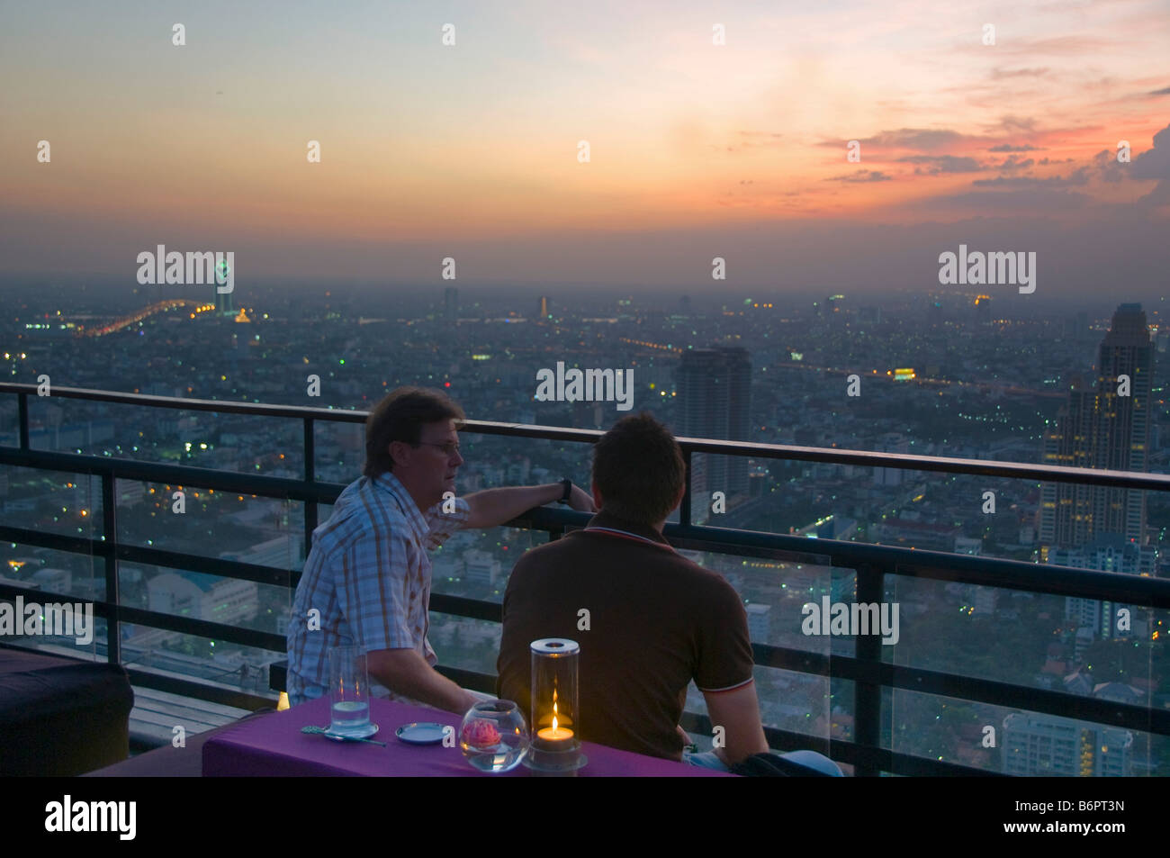 tourists enjoying drinks at sunset on a rooftop bar in Bangkok Thailand Stock Photo