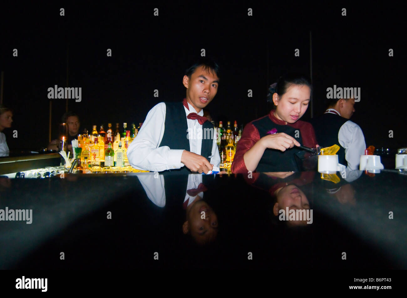 bartender mixing drinks at night on a rooftop bar in Bangkok Thailand Stock Photo