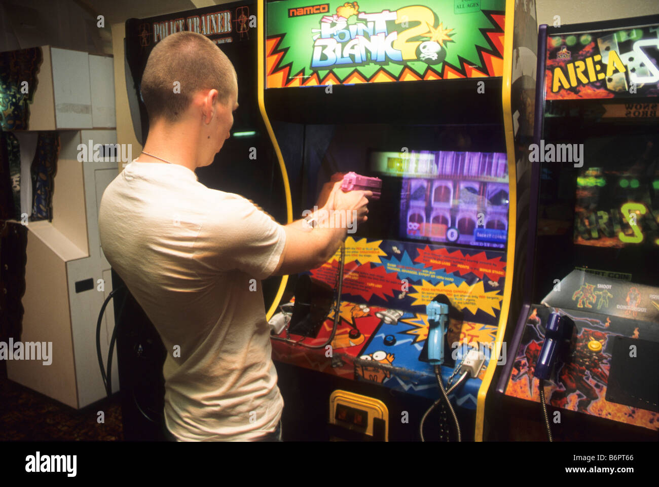 Teen boy plays arcade shooting game Stock Photo