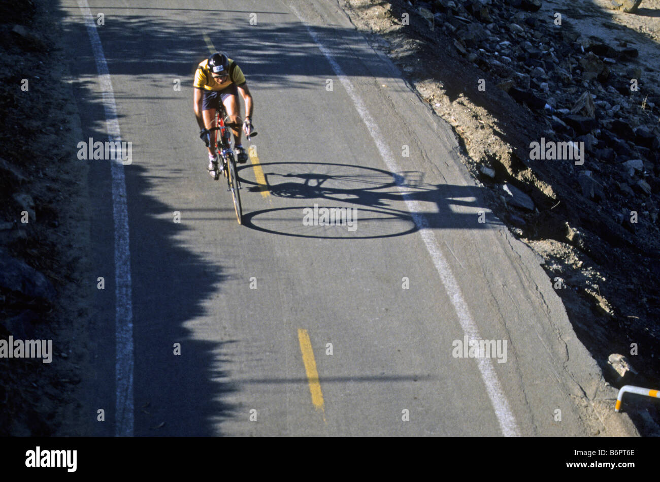 Bike rider races his shadow on bike trail in Anaheim, California Stock Photo