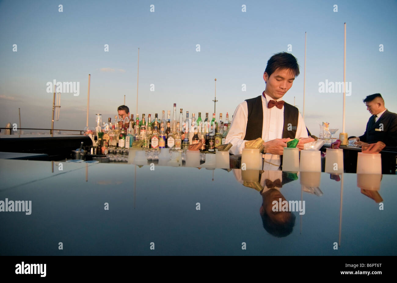 bartender mixing drinks at sunset on a rooftop bar in Bangkok Thailand Stock Photo