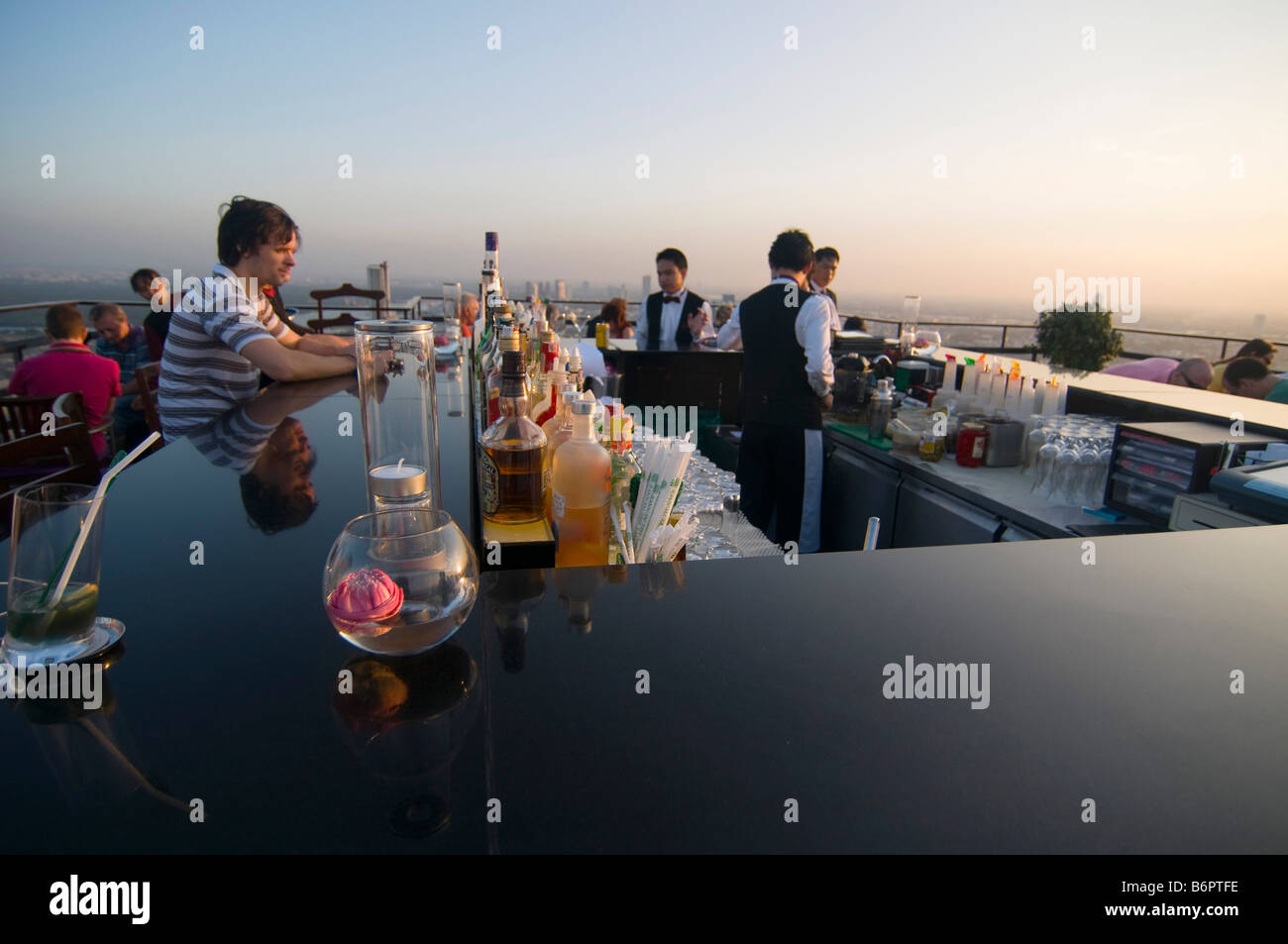 tourists having drinks at sunset on a rooftop bar in Bangkok Thailand Stock Photo