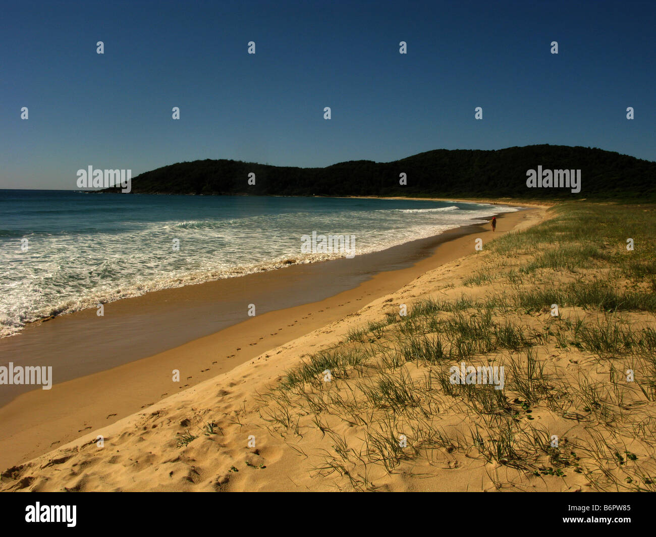 A lone woman walks on the beach at Delicate Nobbys near Crescent Head New South Wales Australia Stock Photo