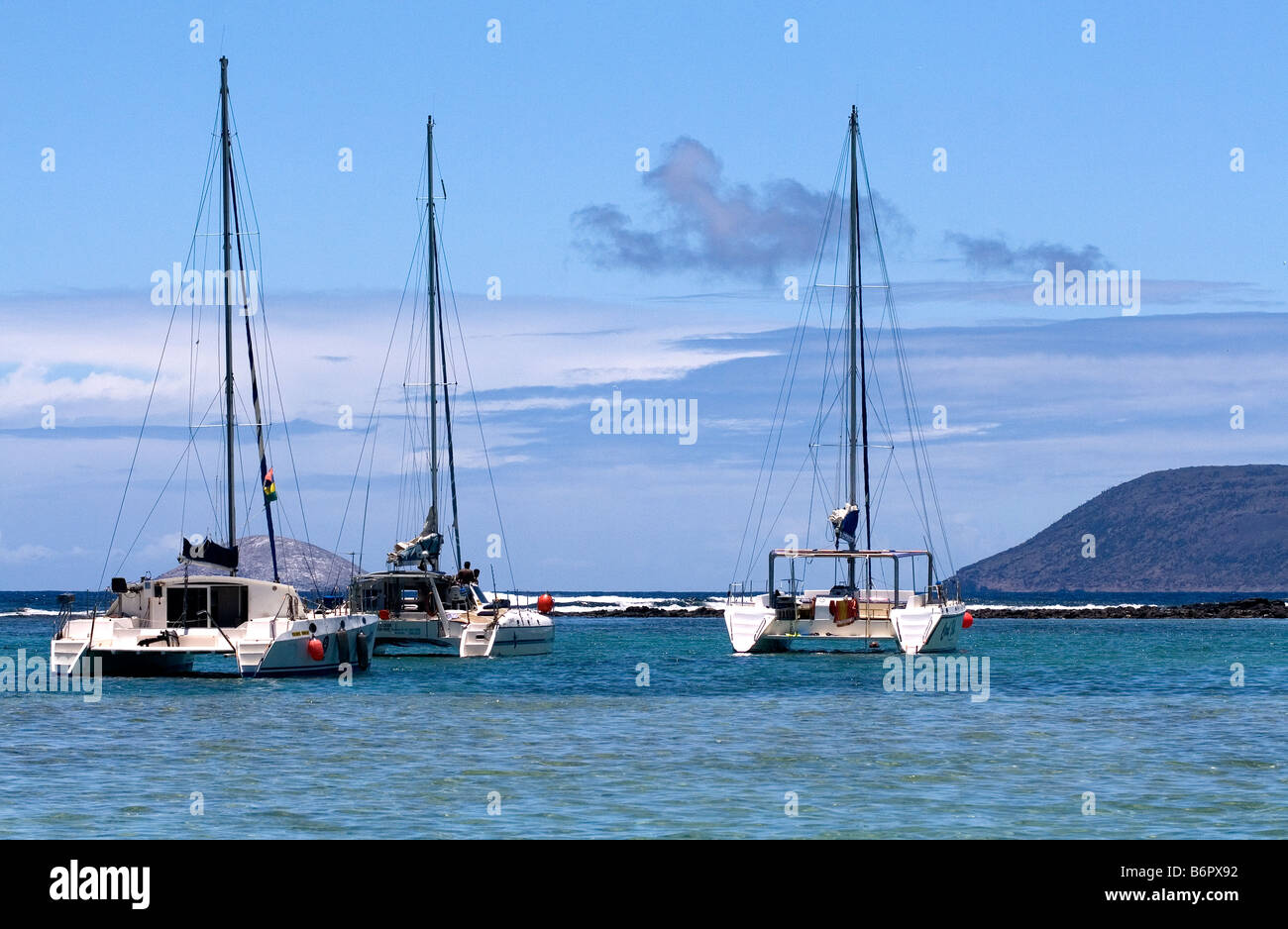 Three catamarans moored on a reef between Ile Plate & Ilot Gabriel with Ile aux Serpents & Ile Ronde in the distance, Mauritius. Stock Photo