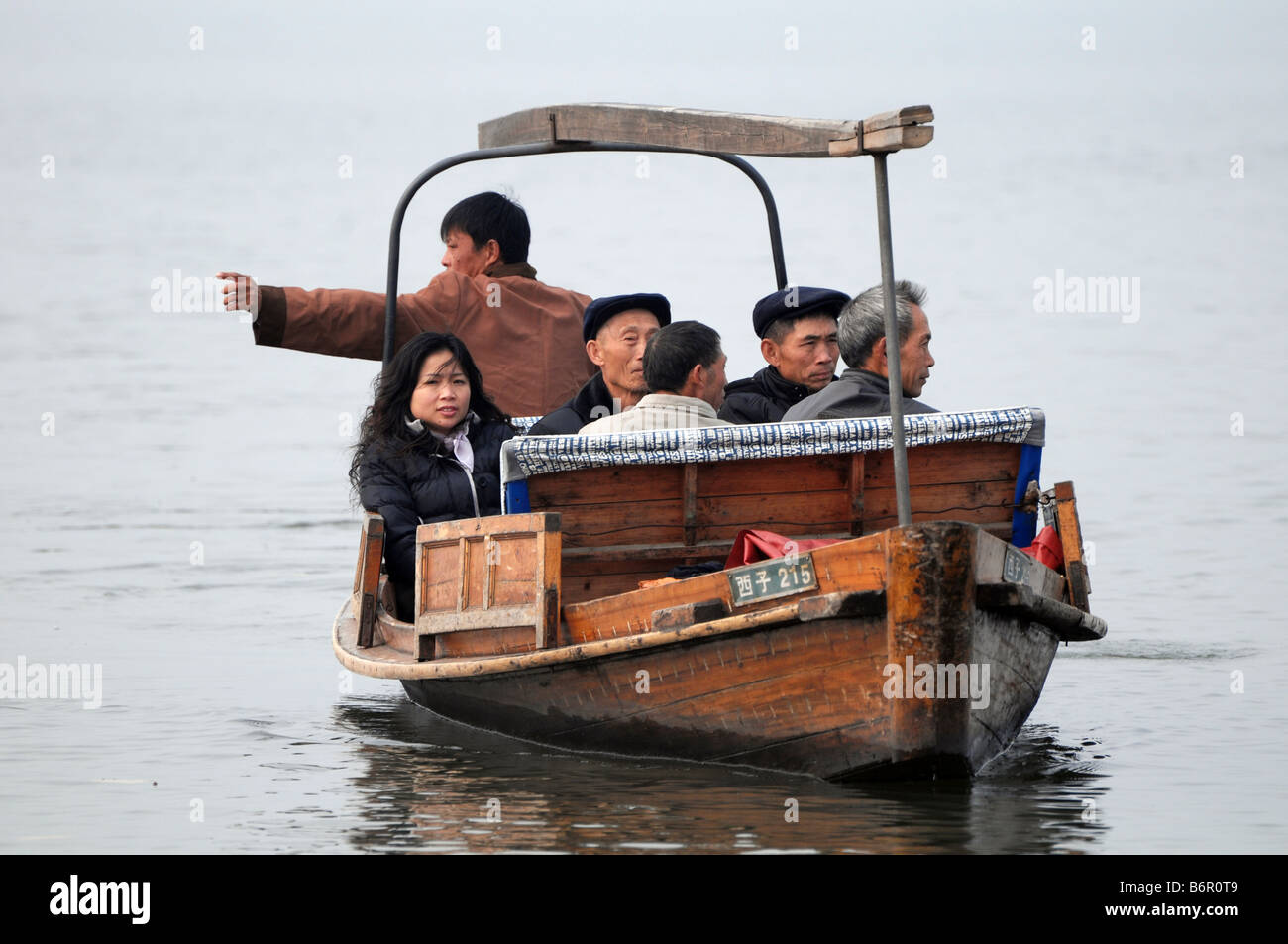 Chinese tourists ride on a boat in Hangzhou's famous West Lake in winter, China. Stock Photo