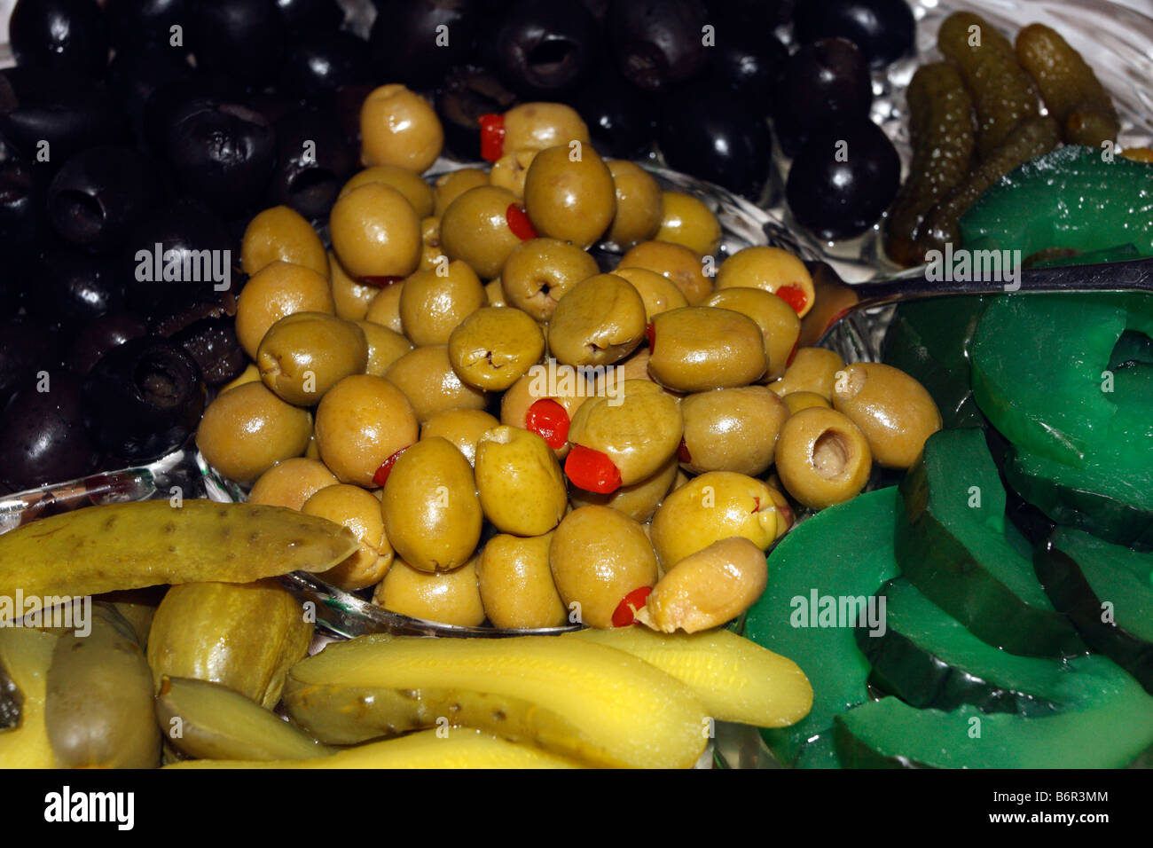 Green olives with pimiento in pile surrounded by black olives, dill