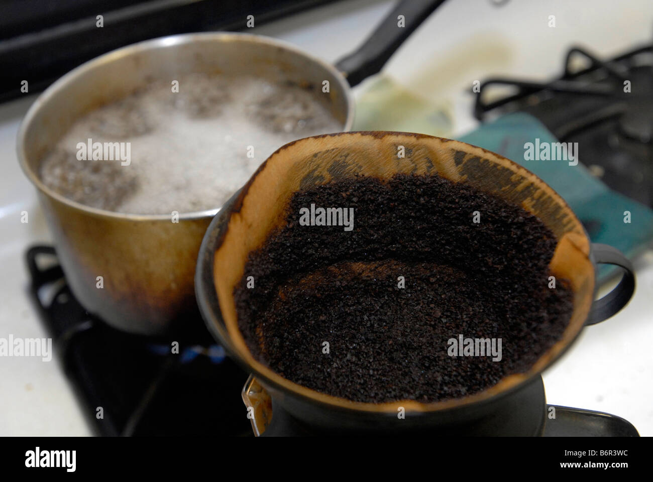 A coffee filter filled with used coffee grounds sits on a stove top in