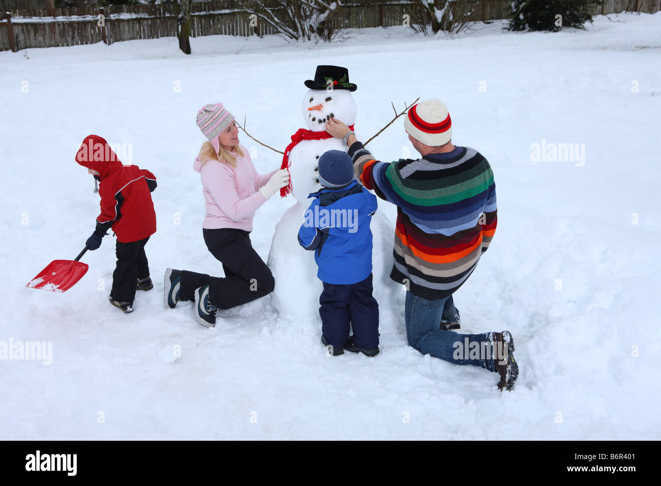 Family in winter building snowman together Stock Photo - Alamy