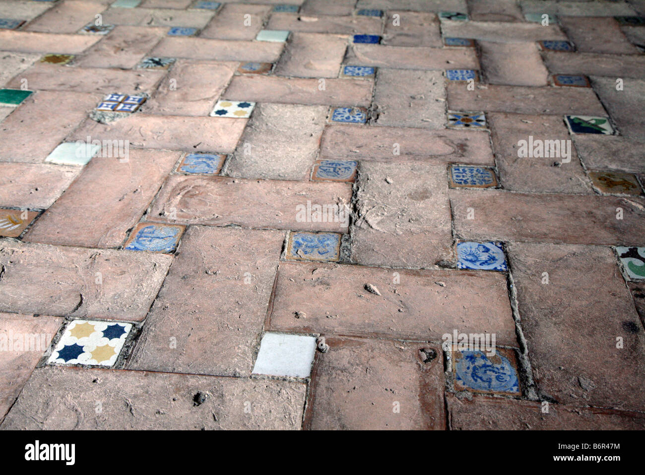 Colourful floor tiles amongst terracotta tiles inside a house in Spain Stock Photo