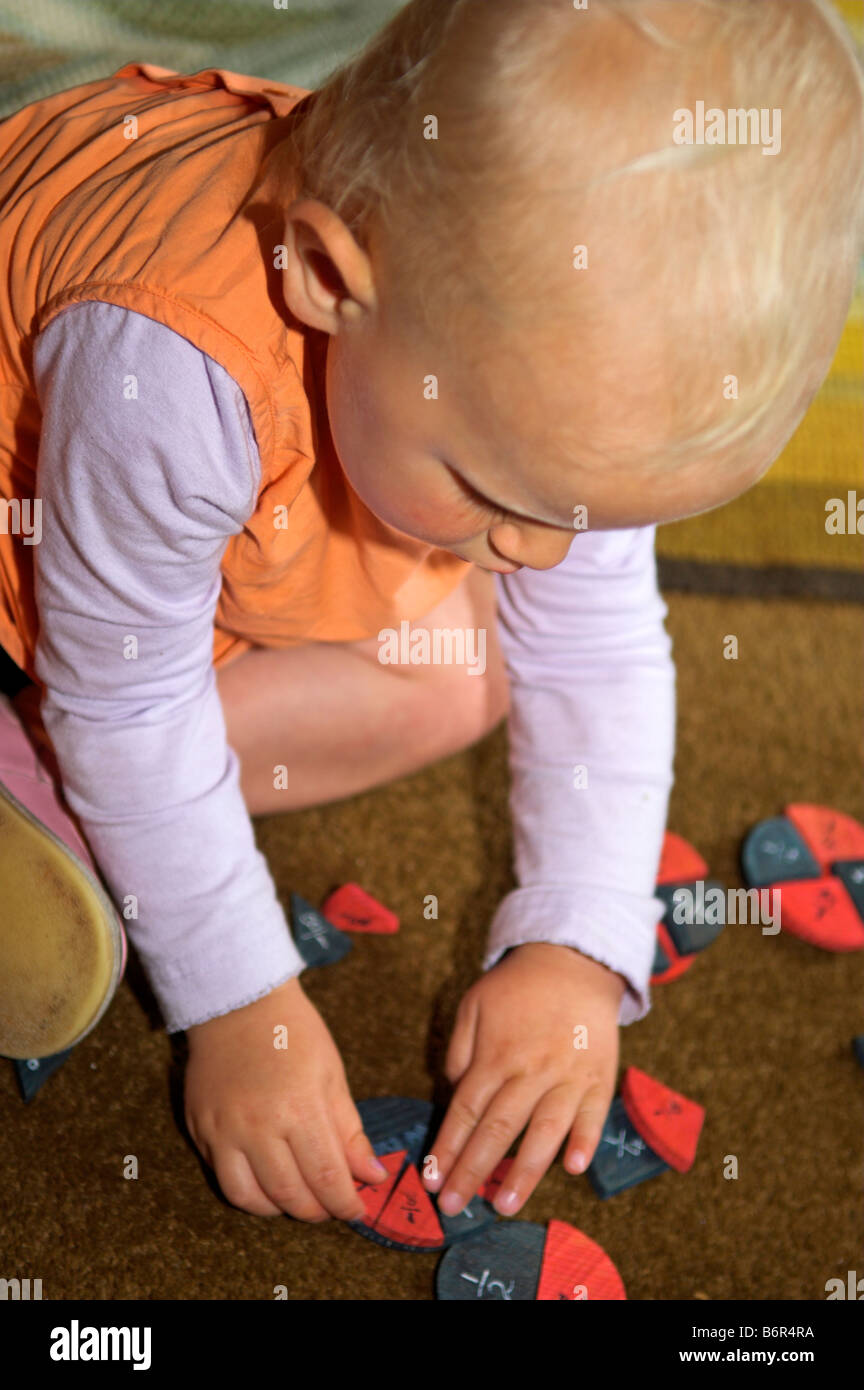 Two year old girl arranging shapes of educational game Stock Photo