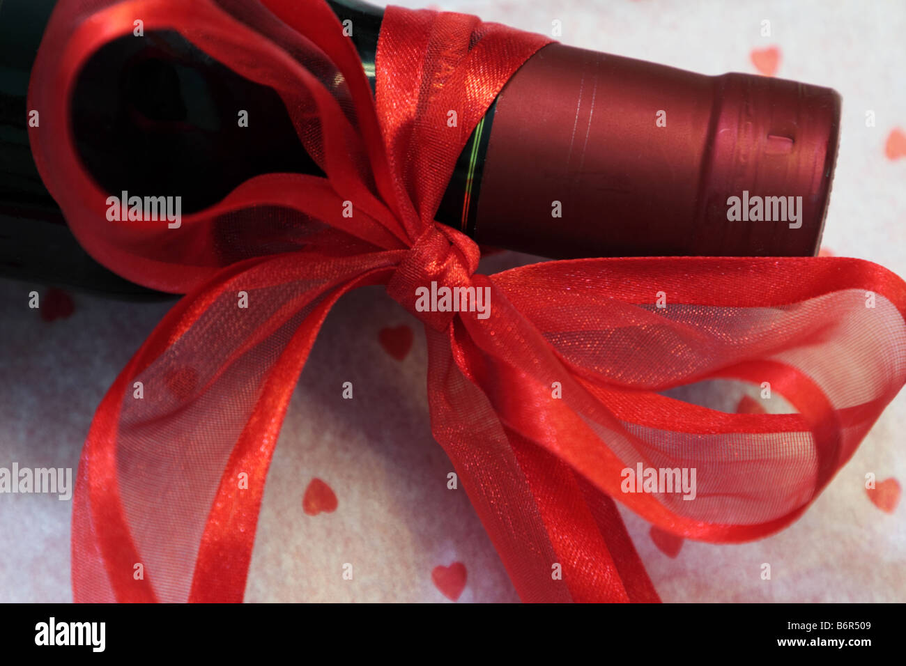 Red wine with ribbon and heart dotted wrapping paper for Valentines Day Stock Photo