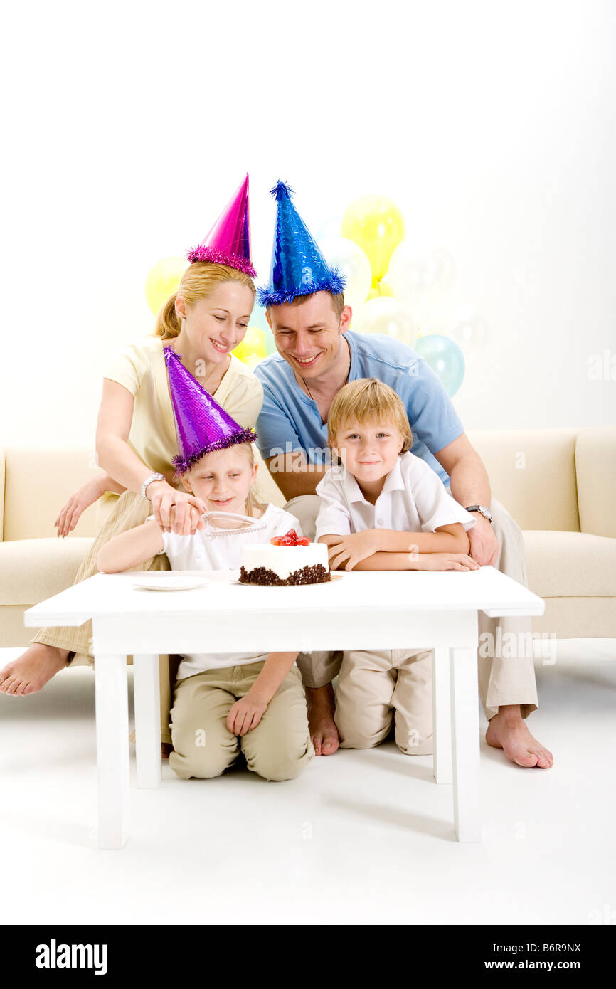 Mother helping son cutting birthday cake while others waiting portrait Stock Photo