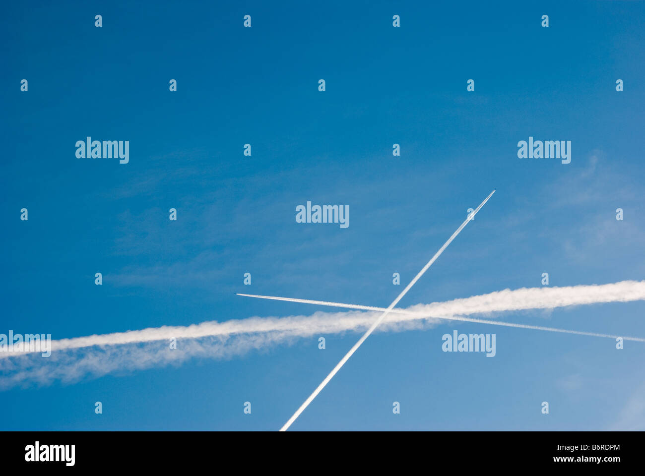 Condensation trails from commercial aircraft flying in different directions. Stock Photo