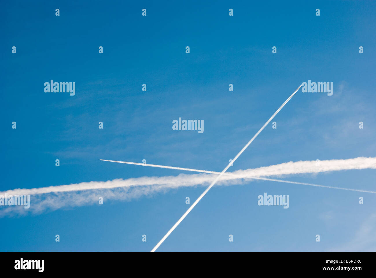 Condensation trails from commercial aircraft flying in different directions. Stock Photo