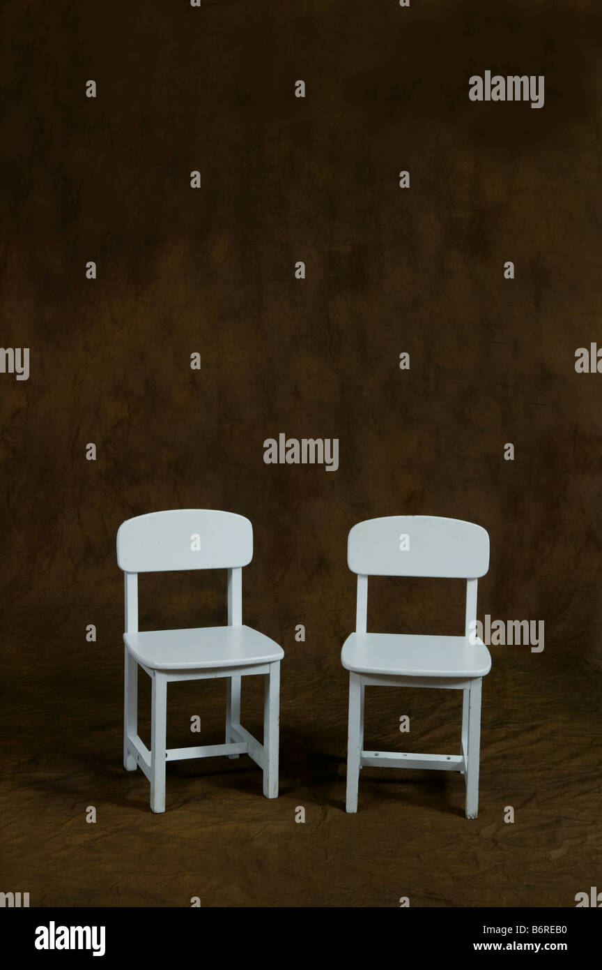 two small white chairs on brown studio background with large areas for copy all around pair Stock Photo