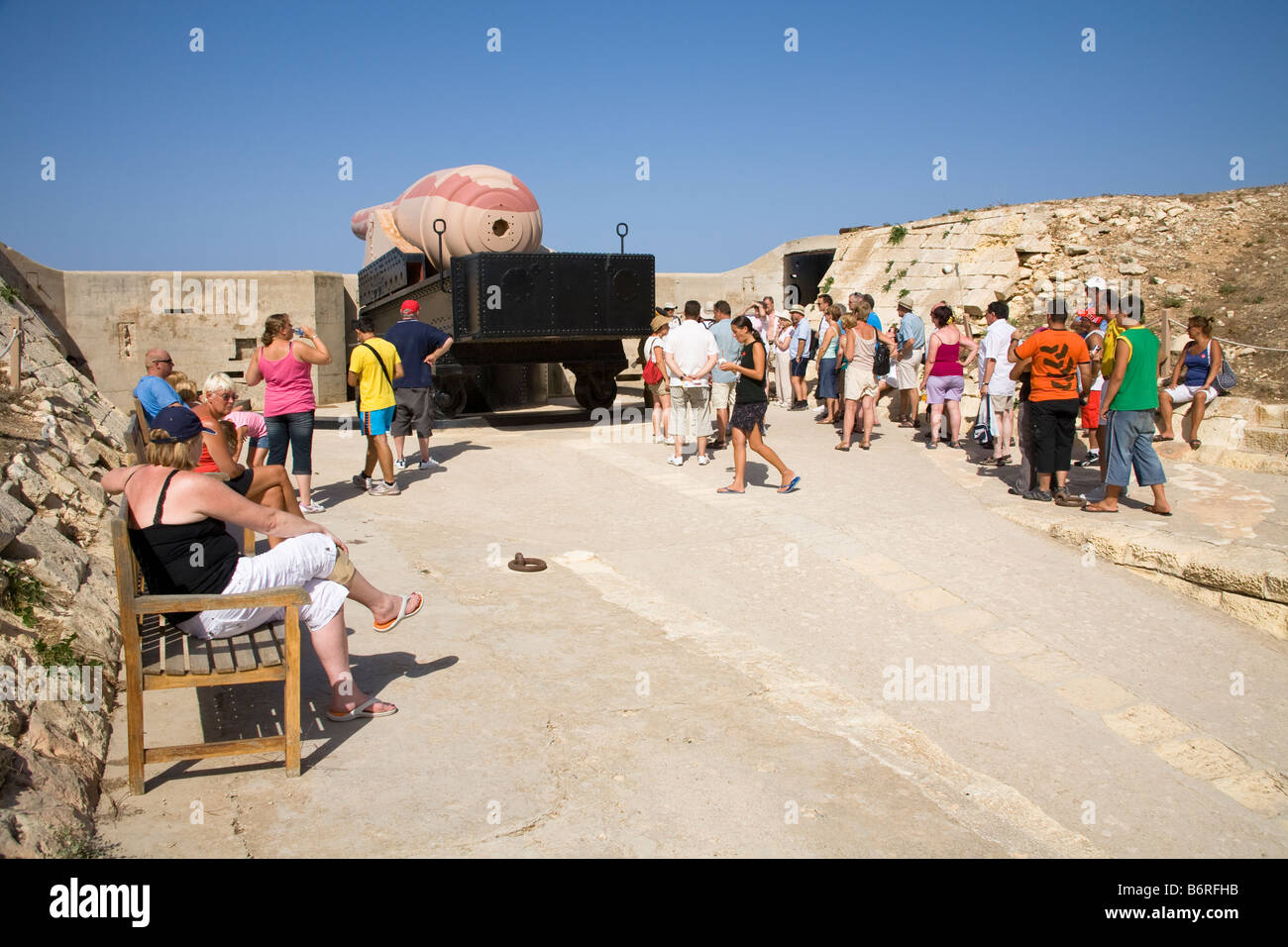 Tourists standing beside The Armstrong 100 ton gun, Fort Rinella, Kalkara, Malta Stock Photo