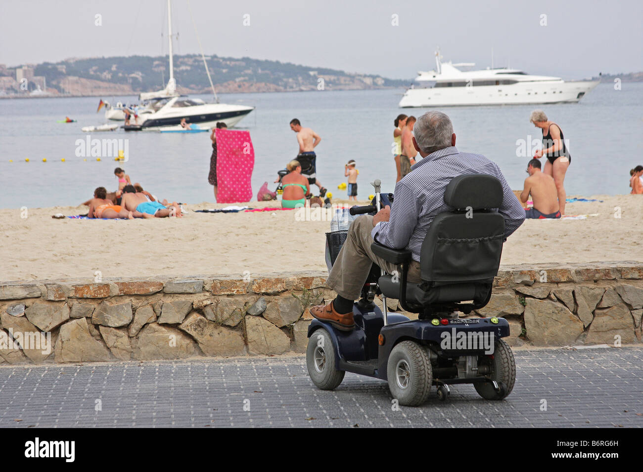 Man on powered wheelchair or buggy parked near the beach at Palma Nova. Stock Photo