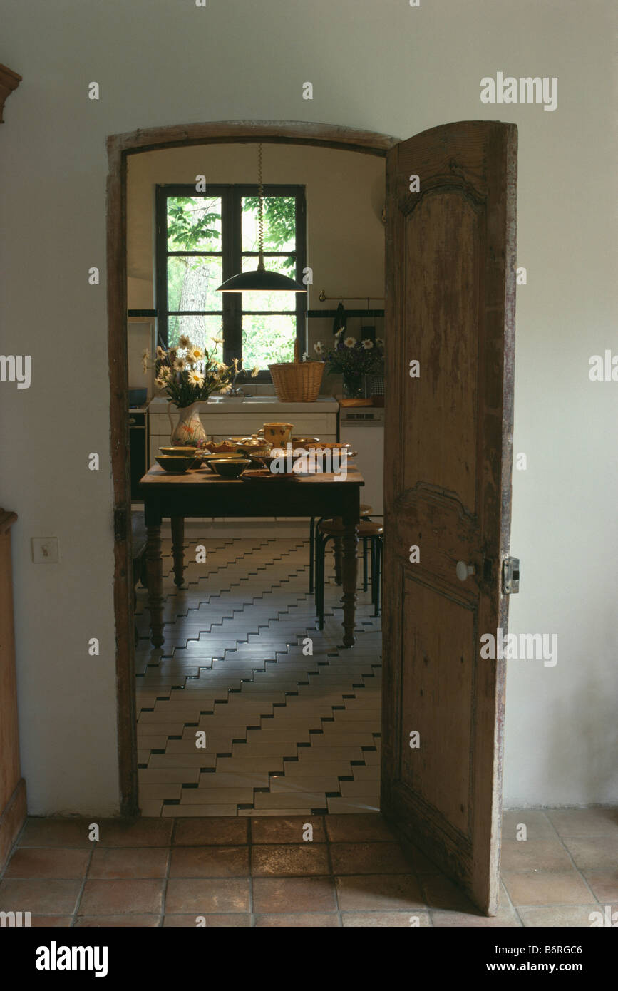 View from hall through open door to country kitchen with pottery bowls on  wooden table in front of window Stock Photo - Alamy, image size:867x1390