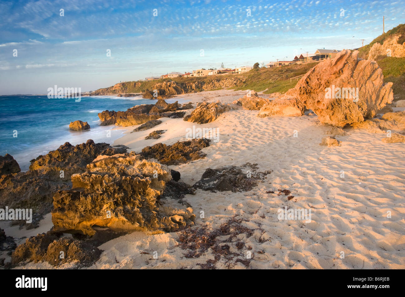 Limestone rocks at Trigg Beach with houses above the cliffs. Perth