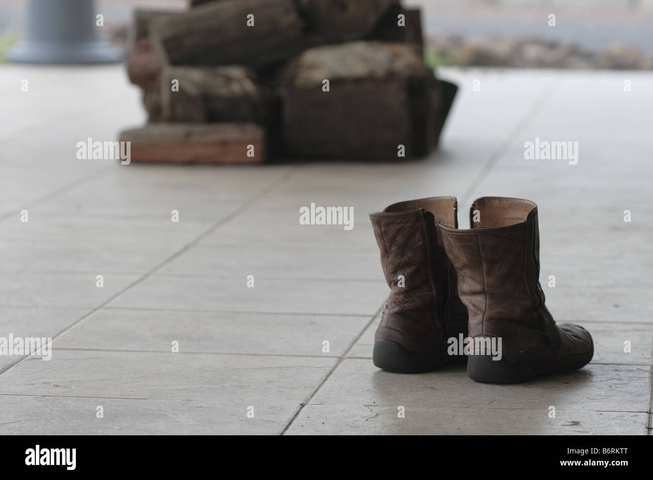 A pair of boots sits on a verandah firewood in the background Stock ...