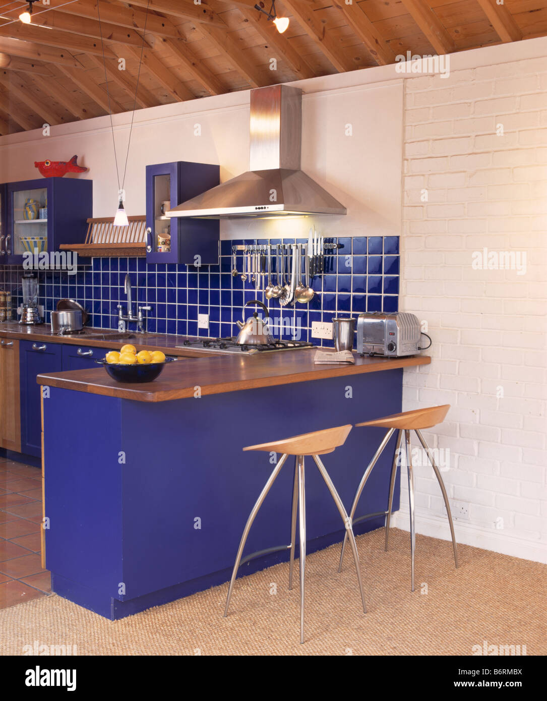 Wood and metal stools at breakfast bar with wooden worktop in modern