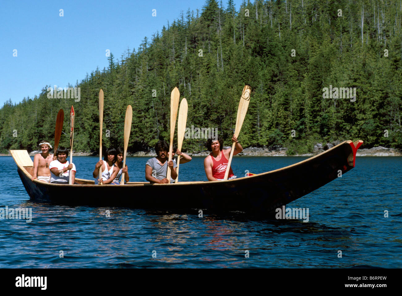 Native American Indians canoeing in a Traditional Dugout Canoe near Bella Bella on the West Coast of British Columbia Canada Stock Photo