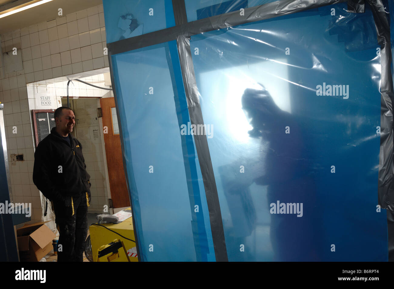 Man in full protective clothing inside a secured environment cleaning