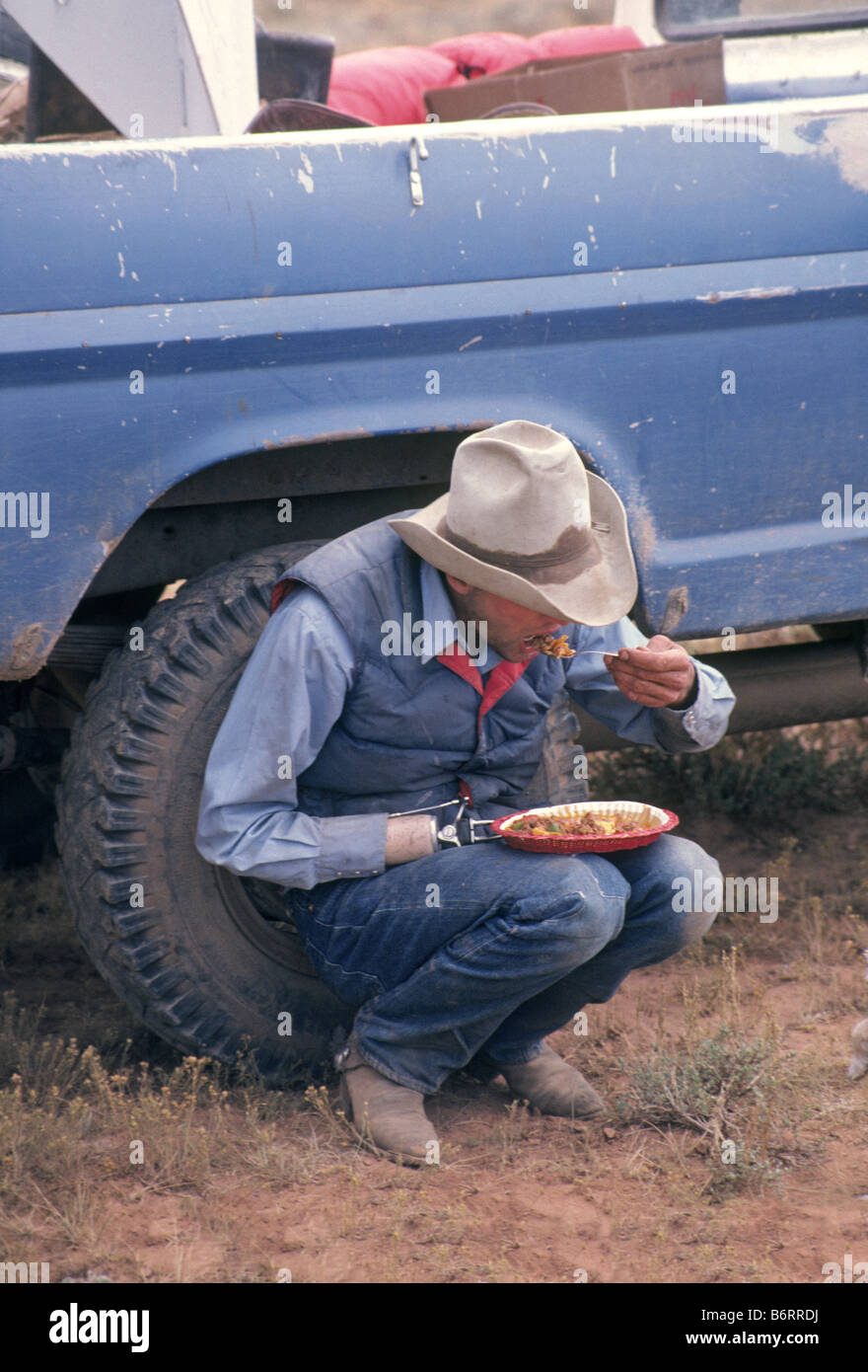 A one armed cowboy eats lunch on a cattle drive on a small cattle ranch in southern Colorado Stock Photo