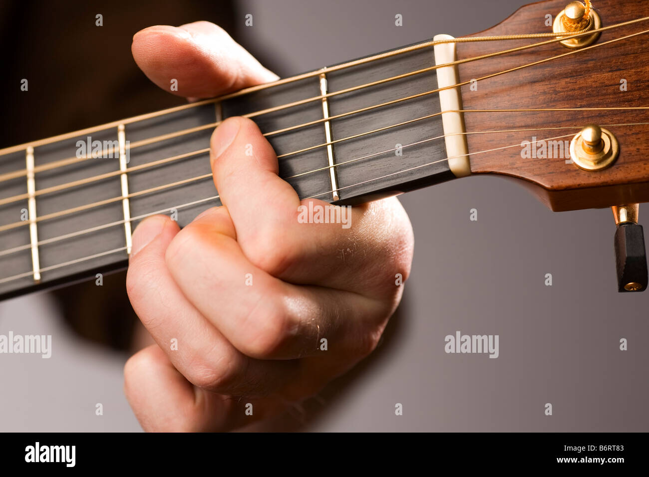 Close up of acoustic guitar players left hand fingering a chord Stock