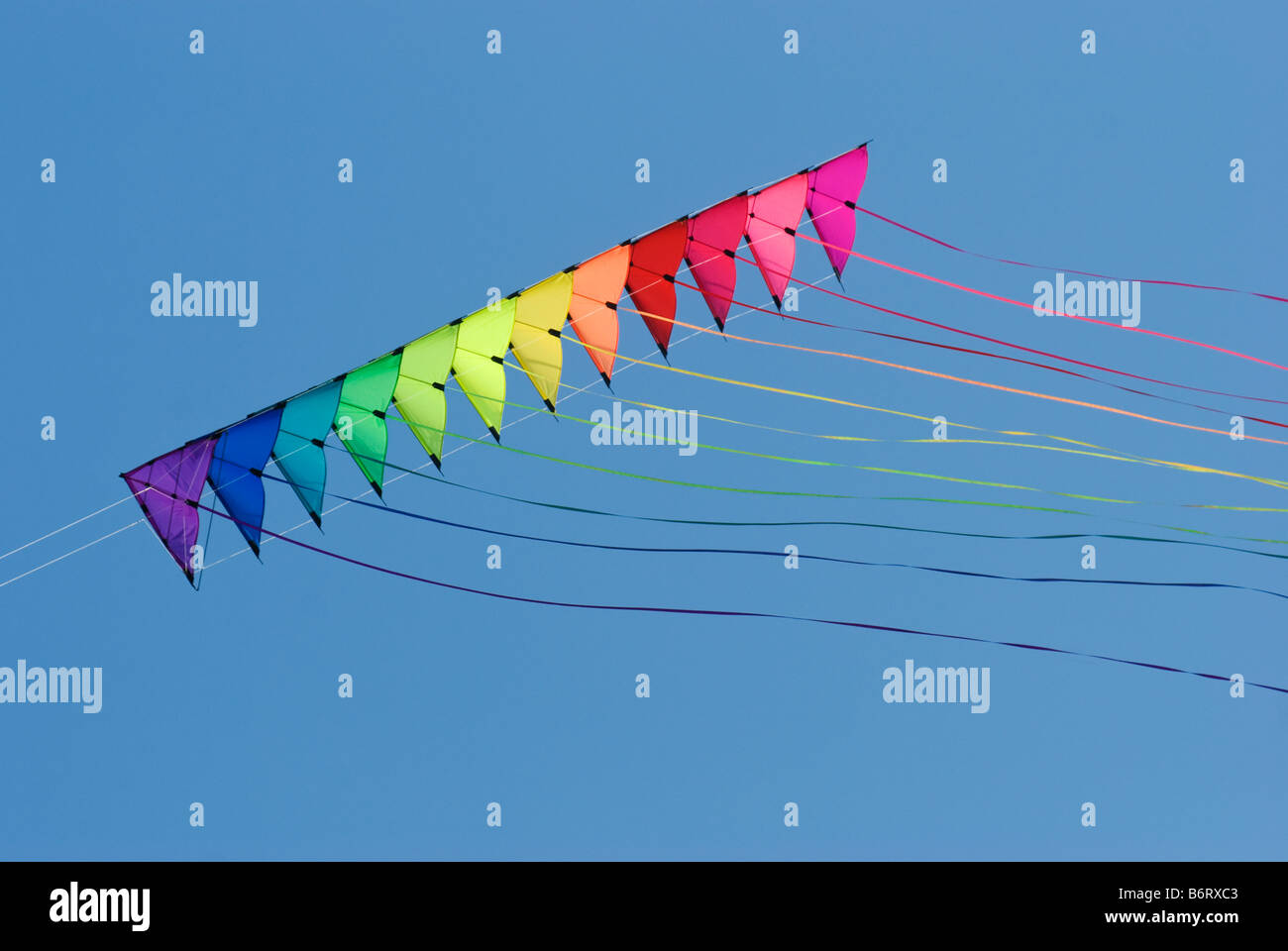 Stack of 12 stunt kites in rainbow colours on a blue sky background Stock Photo