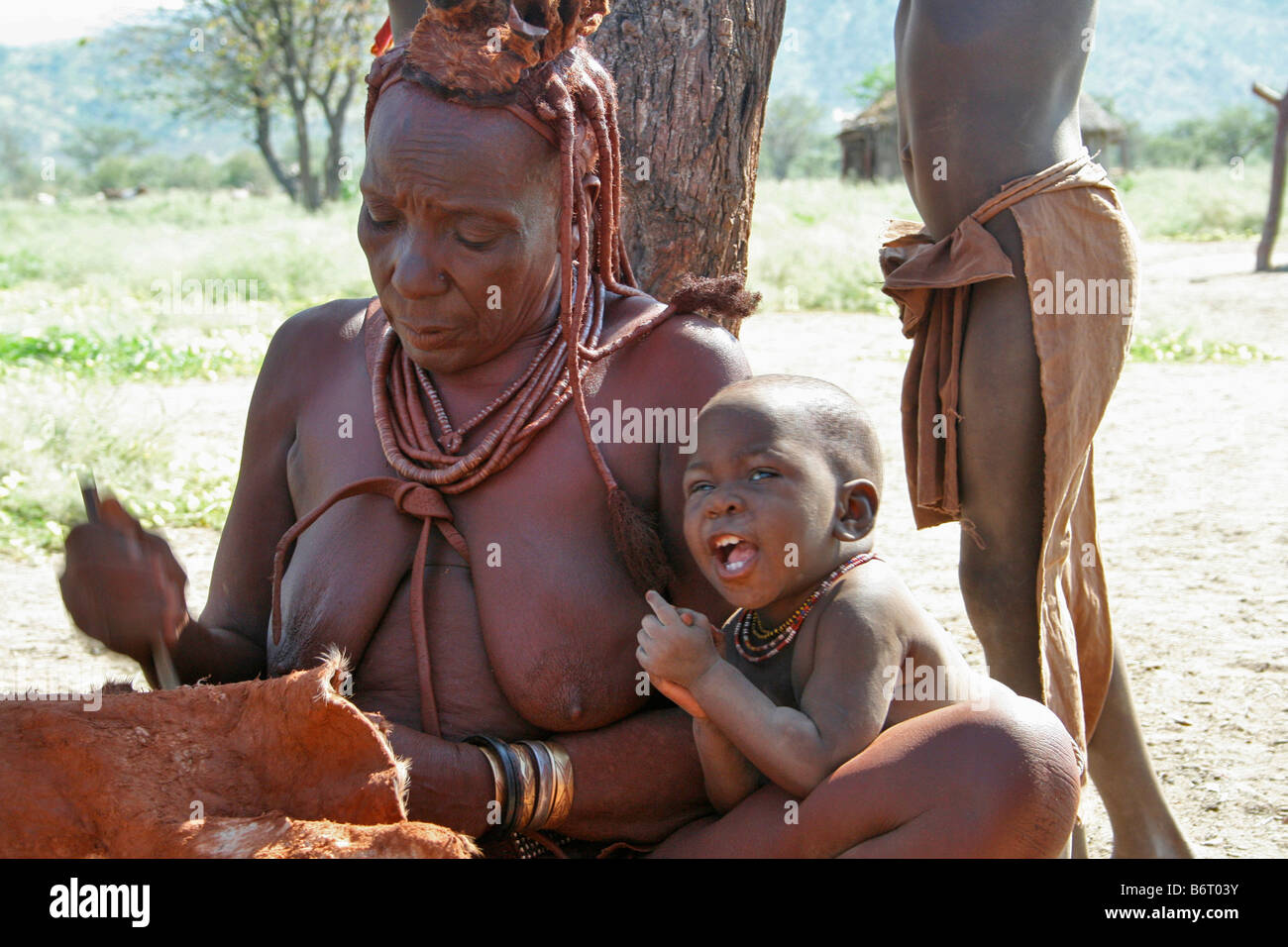Himba woman preparing a goat skin Stock Photo