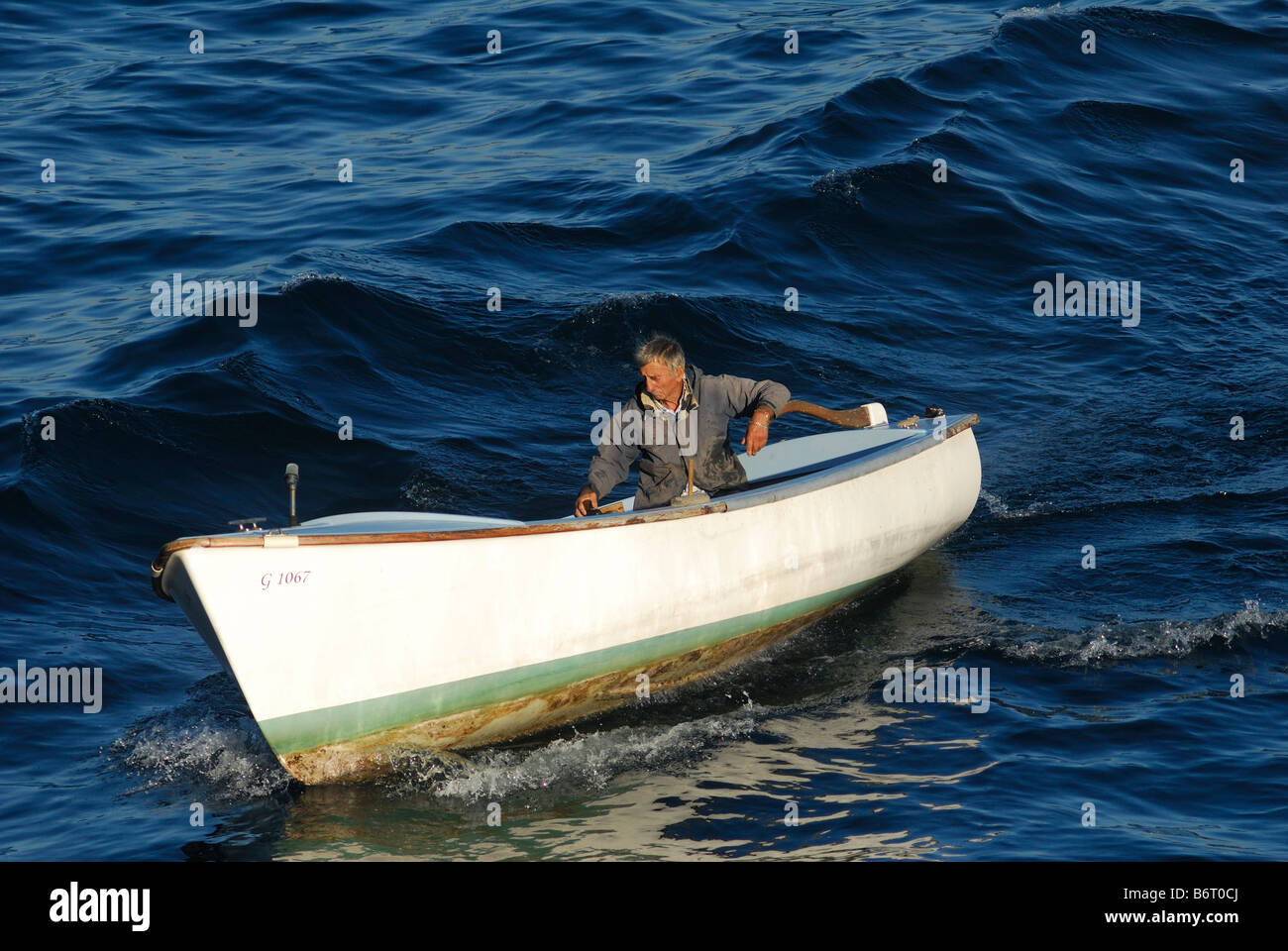 Old man fishing fishing with hand line from small motor boat Stock