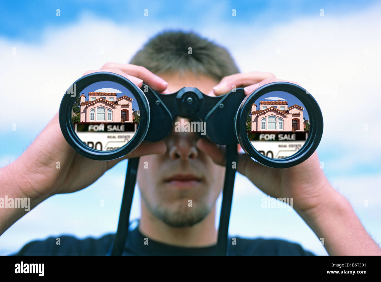 teenage boy looking through binoculars at property for sale Stock Photo