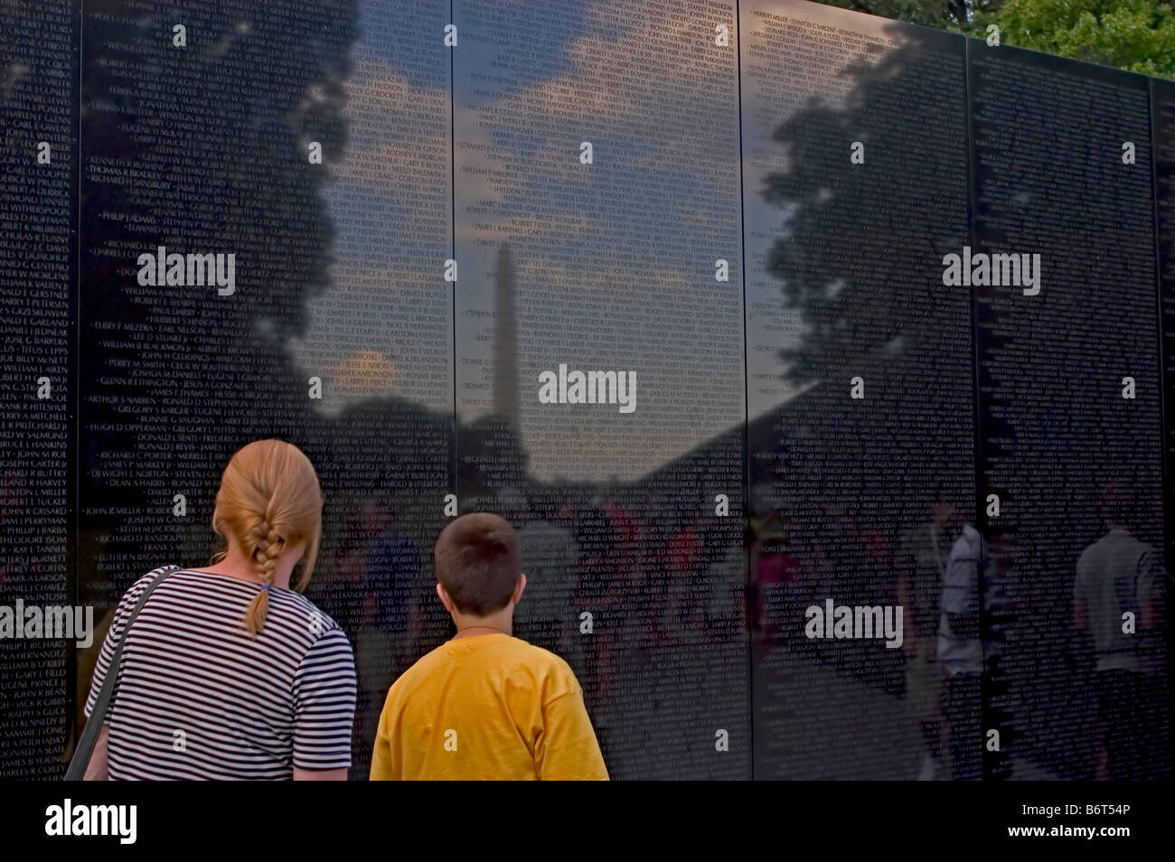 Mother and son read names on Vietnam Memorial, Washington, DC USA Washington Monument appears in reflection with soldier names. Stock Photo
